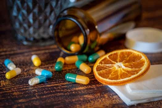 Close-up of vitamins, pills, and dried orange slice for cold relief.