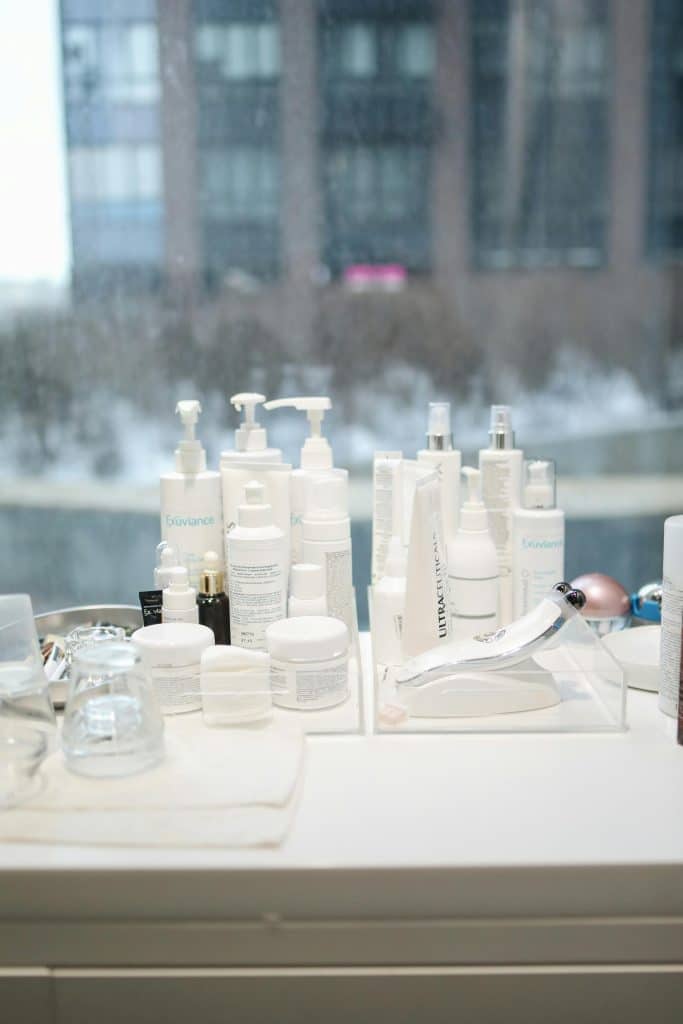 Skincare products arranged on a table by a window with a city view in the background.