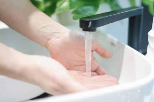 Hands washing under a modern bathroom faucet, emphasizing hygiene and cleanliness.