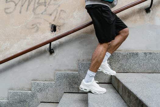 Adult male in athletic attire climbing stairs outdoors, emphasizing fitness and energy.